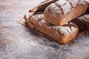 Freshly baked sourdough rye flour bread with sunflower and pumpkin seeds on a brown napkin.