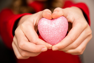 Obraz premium White Caucasian White Caucasian Female hand close up giving, holding glitter sparkle heart. Valentine day. February 14. Love concept 