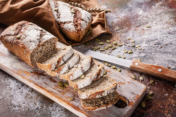 Freshly baked sourdough rye flour bread with sunflower and pumpkin seeds on a brown napkin. Sliced...