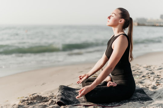 Young Sporty Woman Practice Yoga Meditation On The Beach Near Ocean Facing Sun