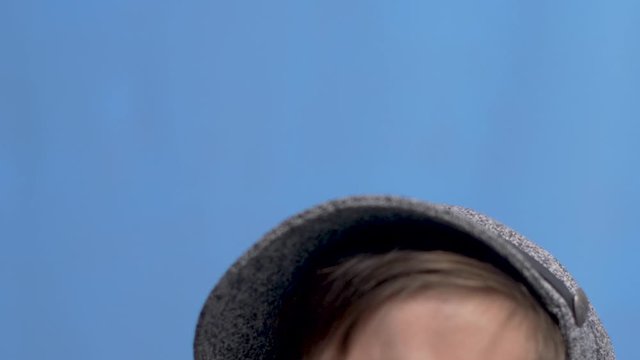child with a gray gray mustache and a hat stands in the Studio
