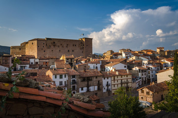 A panoramic view at sunset of the medieval village of Mora de Rubielos with a tile roof in the foreground and the great castle on the left in the background, Teruel, Spain