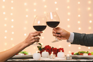 Romantic couple clinking glasses with red wine on date in restaurant