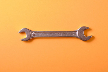 Chrome wrench on a yellow background, top view