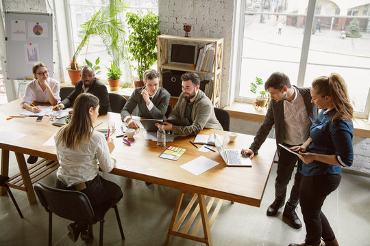 Top view. Group of young business professionals having a meeting. Diverse group of coworkers discuss new decisions, plans, results, strategy. Creativity, workplace, business, finance, teamwork.