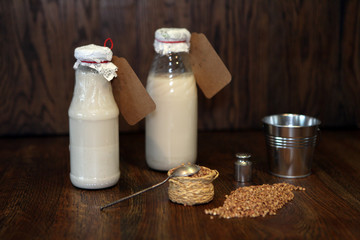Buckwheat milk in a bottle and buckwheat in a glass jar on a light background. Delicious Botteled milk product for vegans. Healthy organic nutrition concept