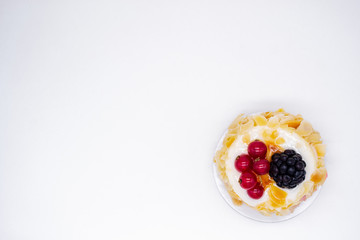 Close up of a сream cake with almond petals, red currants and blackberries.  Concept of holiday, birthday, sweet life, Valentine's day