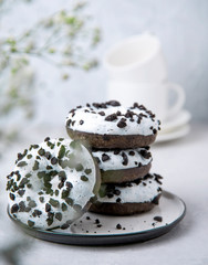 several delicious fresh hearty black and white doughnuts are stacked in a white plate on a white background
