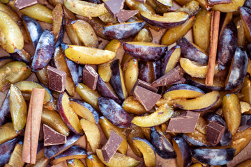 Fresh plum fruit cut into slices, slices with cinnamon sticks, chocolate, cloves. Preparation of ingredients and fruits for making delicious jam.