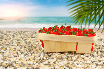 Strawberries in a basket on the shore of the warm sea.