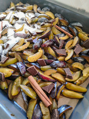 Fresh plum fruit cut into slices, slices with cinnamon sticks, chocolate, cloves. Preparation of ingredients and fruits for making delicious jam.