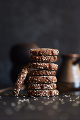 Vegetarian gluten free dessert. Homemade chocolate cookies with sesame seeds in pile on black background copy space