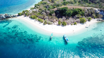 A drone shot of a paradise island with some boats anchored around in Komodo National Park, Flores,...
