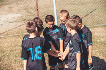 Boys standing in circle with stack of hands together showing unity