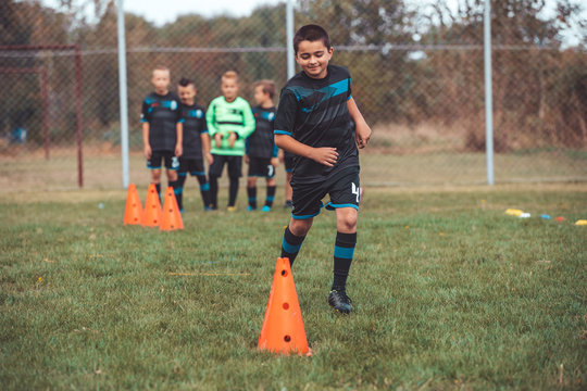 Young Player In Soccer Jersey Running Between Cones And Ring Ladder Marker