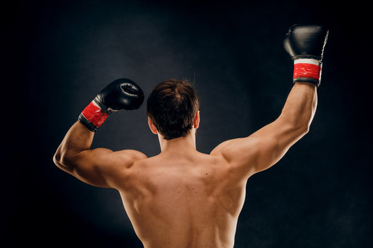 Back view of man boxer with raised hands in victory gesture. Concept of hard sport, glory and success