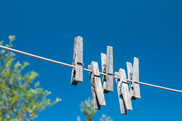 Weathered wooden laundry clamps hanging on a string on blue sky background