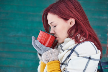 beautiful girl is drinking a hot drink in the winter in nature, tea, coffee