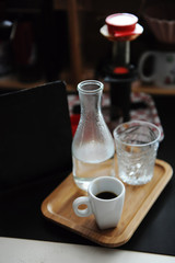 Home coffee brewing still life. Espresso shot with bottle of water on tray. Manual espresso maker