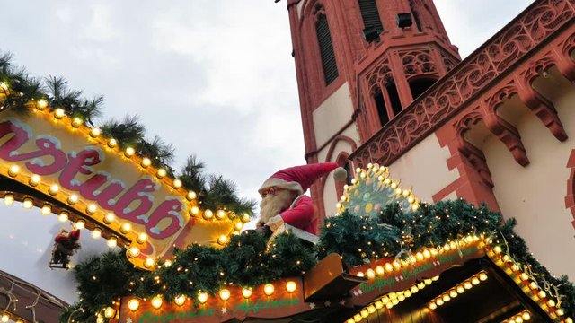 Mu&ntilde;eco de Papa Noel junto a luces navide&ntilde;as y campanario de iglesia