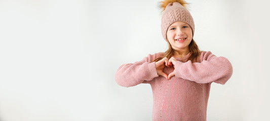 caucasian girl child makes heart shape with hands