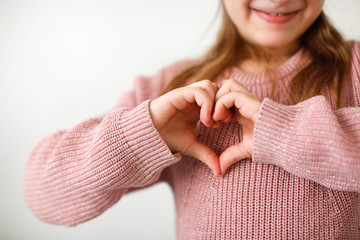 caucasian girl child makes heart shape with hands