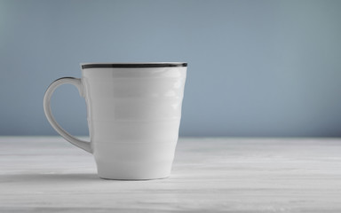 Blank white mug mock up on white wooden table and blue background
