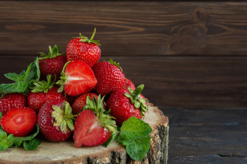 Heap of ripe strawberries on wooden table on blurred background. Organic Berries Closeup. Red, juicy macro photo. Selective focus. Fragaria. Rich in Vitamins, Antioxidants, and Folic Acid. copy space