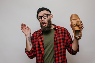 Hipster man holding dirty stinky shoe isolated on white background - obrazy, fototapety, plakaty