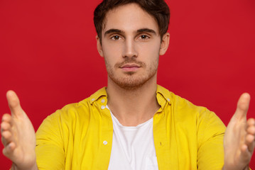Obraz premium selective focus of handsome man in yellow shirt pointing with hands at camera isolated on red background
