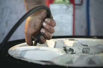 Worker is inflating a car wheel by an inflator at the auto service close up. Defocused image.
