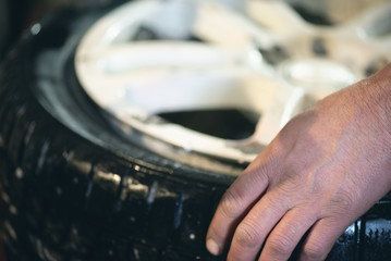 Worker of auto service station is glueing by sealant a wheel rim close up. Defocused image.
