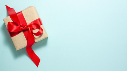 Banner of brown paper gift box with a red satin ribbon bow flat lay