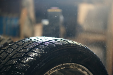 Spraying a car wheel with a soap solution to search for a puncture close up.