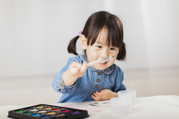 toddler girl practice watercolor paiting at home agianst white background