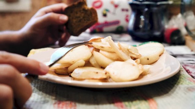 A man eats fried potatoes. Close-up of the plate's hands. Delicious food