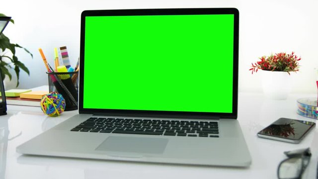 White desk with a laptop. Chroma key. Perfect to put your own images or videos. Colorful desktop elements in the background. Track with perspective corner pin.  