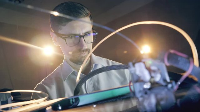 Male engineer is observing a 3D-printing mechanism