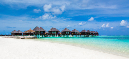 Beach with white sand, turquoise ocean water and blue sky with clouds in sunny day. Natural background for summer vacation. Panoramic view.
