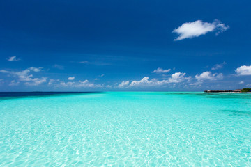Sea and blue sky. Blue sea water and  sky with white fluffy clouds. Horizontal background of blue sea. Tropical landscape