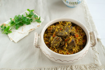 Dish of oriental cuisine - pilaf with lamb in a pan, on a white background.