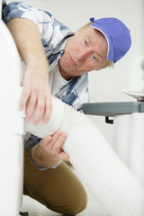 man holding flexible hose in roofspace