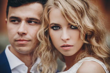 Fototapeta premium Portrait of stylish couple embracing in european city street. Sensual romantic moment. Fashionable bride and groom in love posing with passionate look. Valentines day