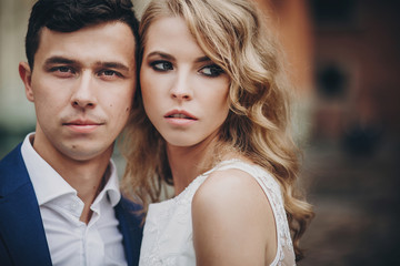 Fototapeta premium Portrait of stylish couple embracing in european city street. Sensual romantic moment. Fashionable bride and groom in love posing with passionate look. Valentines day