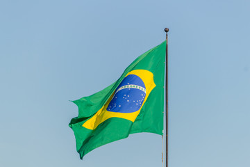 Brazilian flag flying with blue sky background