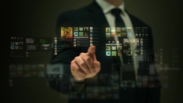 Businessman working on a futuristic holographic interface. Video wall.