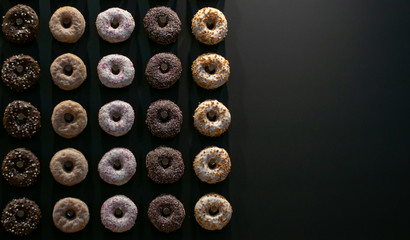 abstract black background of colored donuts with space for your text, sweet dessert