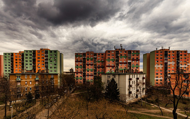 Colorful blocks of flats against a dark stormy sky