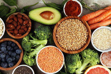 Healthy food clean eating selection: fruit, vegetable, seeds, superfood, cereals, leaf vegetable on rustic background