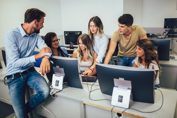 Fototapeta premium College students sitting in a classroom, using computers during class.